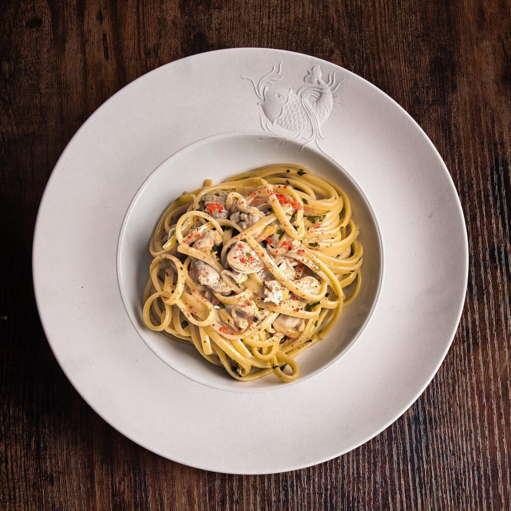 creamy yellow pasta in a white bowl on a brown table