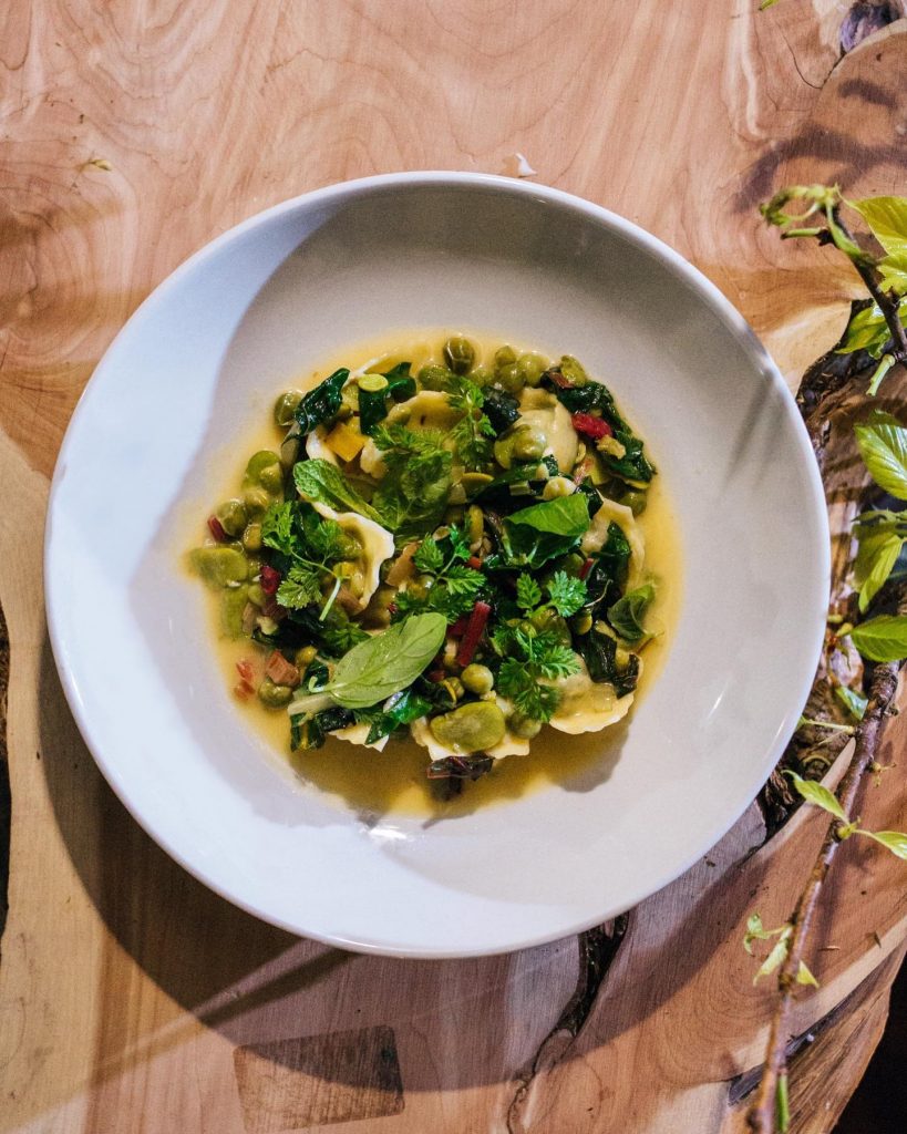 green vegetables in a yellow creamy sauce in a white bowl on a wooden table