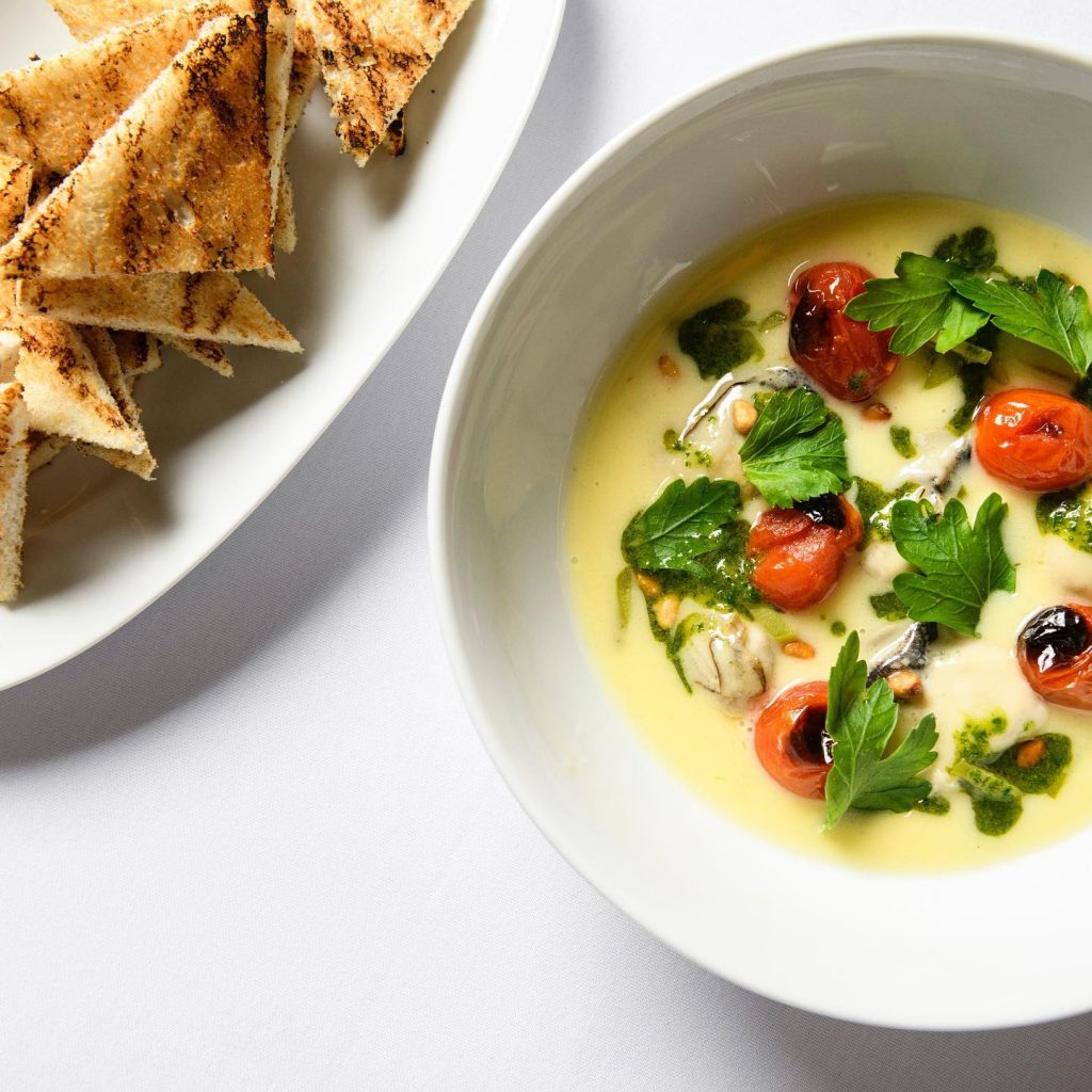 Creamy soup with tomatoes on top and a plate of bread with balsamic glaze.